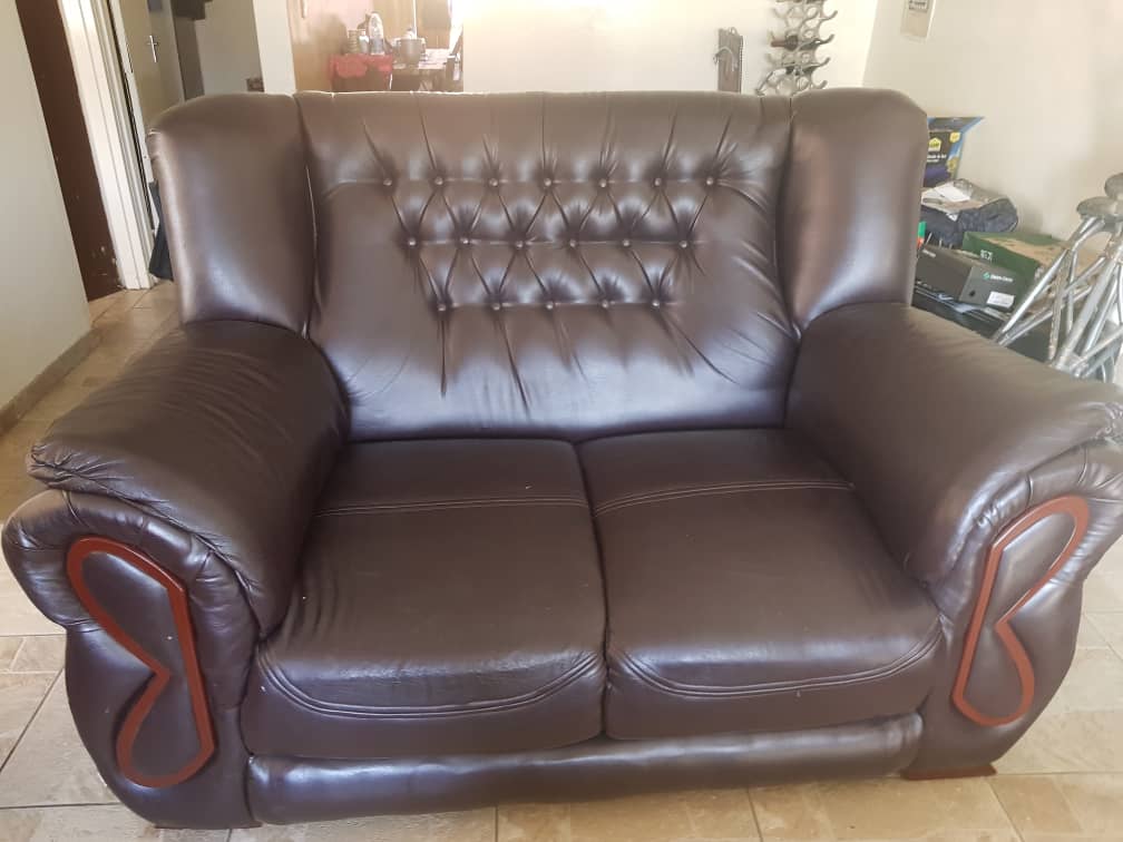 Brown leather two-seater couch with tufted back